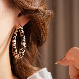 Close-up of leopard print fabric earrings worn by model for vintage aesthetics