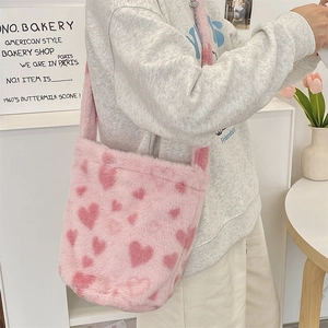 Close-up of pink plush shoulder bag with heart patterns and soft faux fur texture