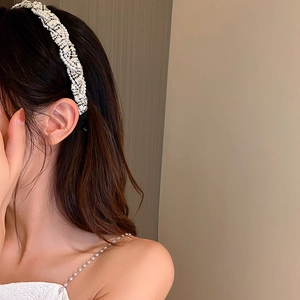 Detail of white pearl and lace woven headband worn by a model for an elegant hair look