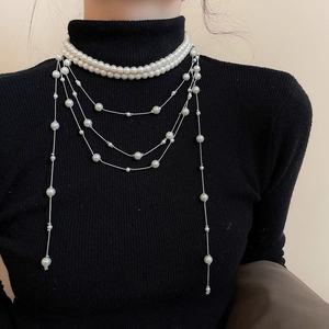 Detail of elegant multi-layer pearl necklace with long tassels on a black sweater