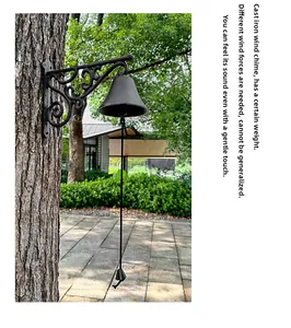 Close-up of a vintage cast iron doorbell with scrolling bracket hanging on a tree trunk