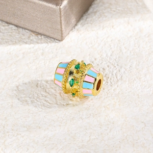 Macro view of gold spacer bead with pink and blue enamel stripes and green zircon stones