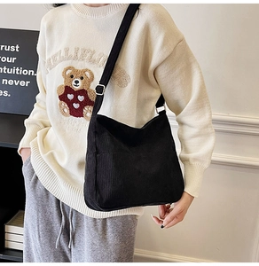Close-up of black corduroy crossbody bag with adjustable strap and front pocket detail