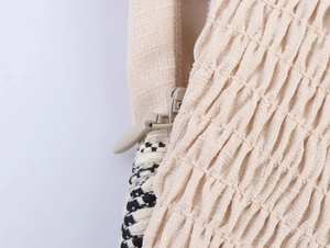 Dettaglio del tessuto beige arricciato con cerniera invisibile e bordo intrecciato