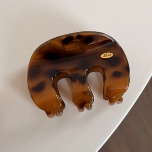 Detail of tortoise shell hair claw clip featuring a small golden oval Love metal plate