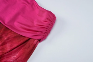 Vue détaillée du tissu en maille rose et du motif tie-dye rouge sur l'ourlet du vêtement