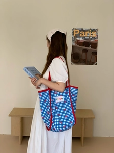 Canvas tote bag with blue plaid design and red bow detail shown on female model