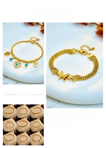 Detail of layered gold titanium bracelets featuring butterfly charms and emerald zircon accents