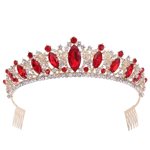 Detail of gold bridal crown with red rhinestones and integrated hair combs on white background