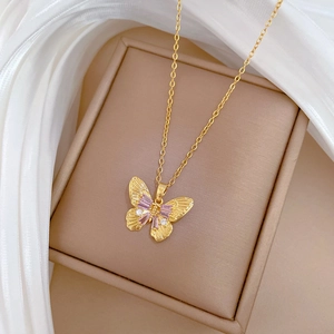 Detailed view of a gold titanium steel butterfly pendant with purple crystals on a gift box