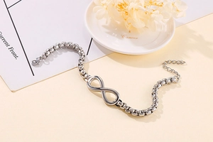 Détail d'un bracelet infini argenté avec chaîne en perles sur fond décoratif