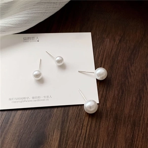 Macro shot of minimalist round white pearl stud earrings on an elegant wooden background