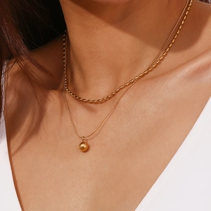 Detail of 18K gold plated double layer necklace with olive beads on female model neck