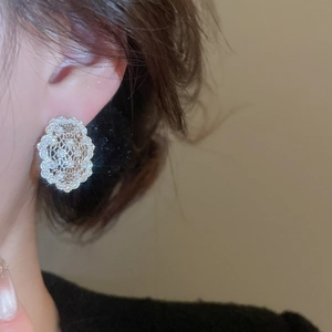Vue macro de boucles d'oreilles en dentelle d'argent avec zircons sur l'oreille