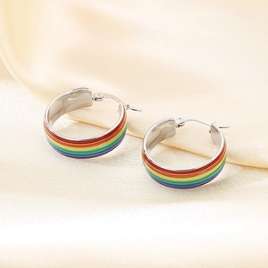 Detail polierter silberner Creolen mit lebhaften Regenbogen-Emaille-Streifen auf Satin