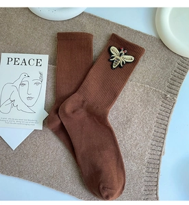 Detail of brown mid-calf socks with colorful bee embroidery on ribbed cotton fabric
