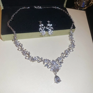 Detailed close-up of crystal leaf and teardrop pendant necklace in a luxury jewelry box