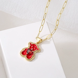 Gold 18K plated bear pendant necklace with red heart gemstone on white platform