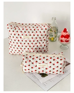 Dettaglio di trousse in cotone trapuntato con motivi di fragole e etichette in tessuto jelly