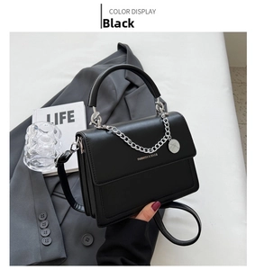 Detail of black crossbody bag featuring silver chain decor and smooth matte texture