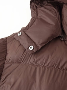 Détail macro de la doudoune à capuche marron foncé avec boutons-pression en métal
