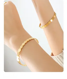 Detail of minimalist gold-plated stainless steel bracelet featuring circular linked discs