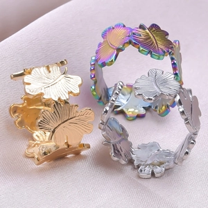 Macro shot of leaf pattern rings in gold, silver and rainbow finishes on silk