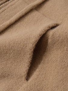 Detailed macro view of brown knitted hoodie fabric texture and side pocket stitching