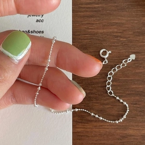 Detail of minimalist S925 sterling silver beaded anklet with heart charm and extension chain
