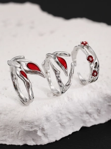Detail of silver punk rings with red resin accents on a natural white stone base