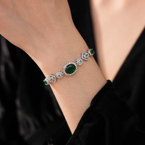 Close-up of vintage emerald and zircon flower bracelet worn on a female wrist