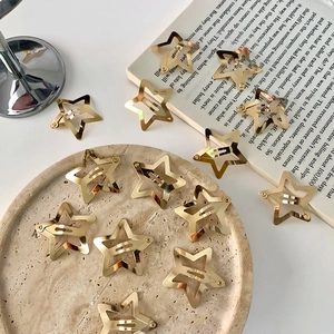 Y2K style gold star hair clips made of polished metal displayed on a decorative stone tray