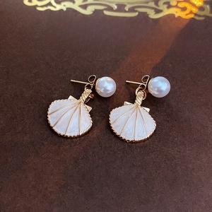 Détail de boucles d'oreilles vintage en forme de coquille avec émail et perle