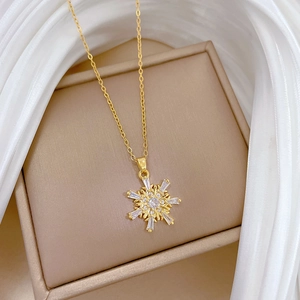 Detailed close-up of a golden snowflake pendant with zircon crystals on a satin background