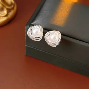 French vintage silver swirl earrings with pearls on a dark textured background