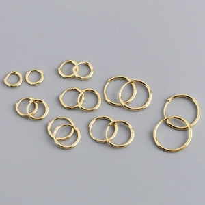 Detailed set of varied gold hoop earrings in multiple sizes on a gray background