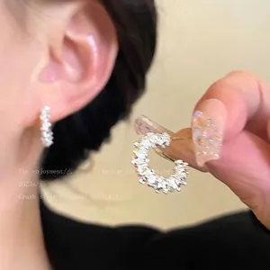 Detail of silver C-shaped hoop earrings featuring sparkling pave set stones on a model