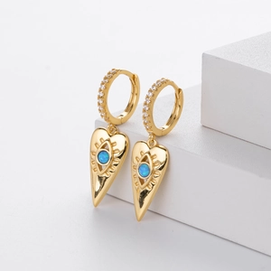 Detailed shot of gold heart earrings featuring blue opal evil eye and sparkling zircons
