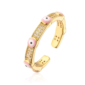 Close-up of gold-plated evil eye ring with pink enamel and micro-set zirconia