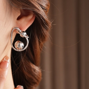 Close-up of a silver twisted metal ball earring worn on a model for a modern look