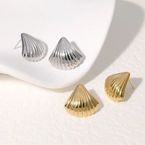 Detail showing gold and silver shell-shaped titanium steel studs on white porcelain