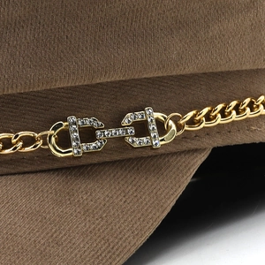 Detail of coffee corduroy military cap featuring golden chain and rhinestone buckle