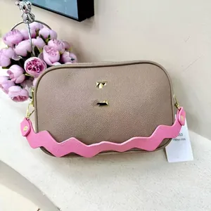Detail of taupe pebbled leather camera bag with pink wavy strap and gold metal logo