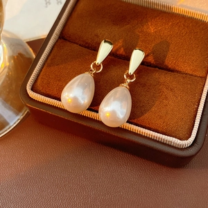 Detailed shot of gold drop pearl earrings displayed in a luxury brown velvet jewelry box