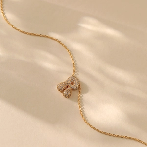 Detailed view of gold plated necklace with a cubic zirconia paved letter R pendant