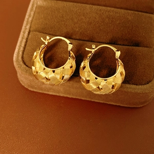 Close-up of 18k gold plated U-shaped woven earrings on a luxury velvet jewelry box display
