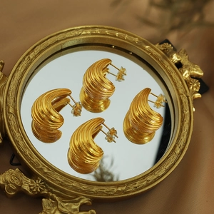 Golden 18K gold-plated titanium stud earrings with a spiral texture on a vintage mirror