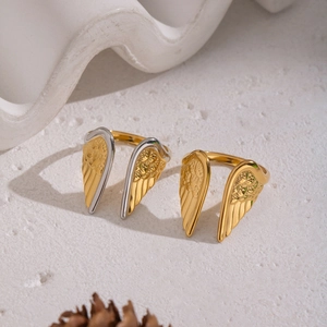 Adjustable 18K gold plated stainless steel angel wing rings on elegant stone props