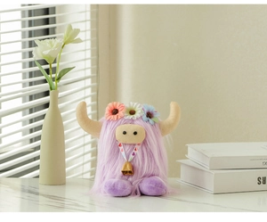 Detail of purple Highland Cow plush toy with floral headpiece and gold bell on a table