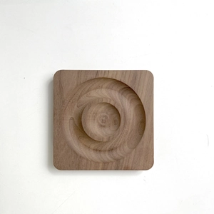 Top view of square wooden display tray with concentric circular grooves for jewelry